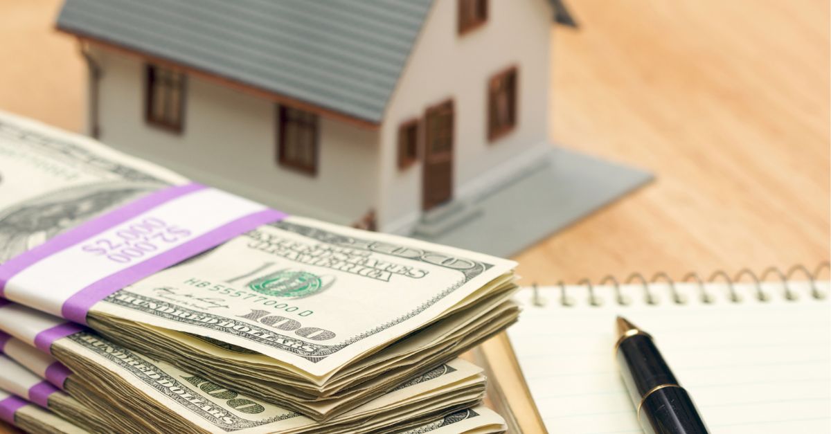 small model of a house with a stack of 100 dollar bills